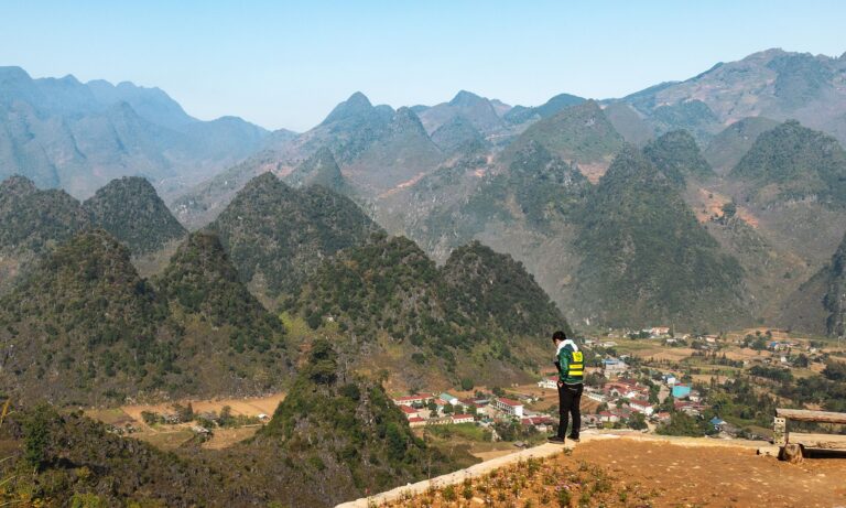 Man standing on a ledge in front of the mountains on the Ha Giang Loop