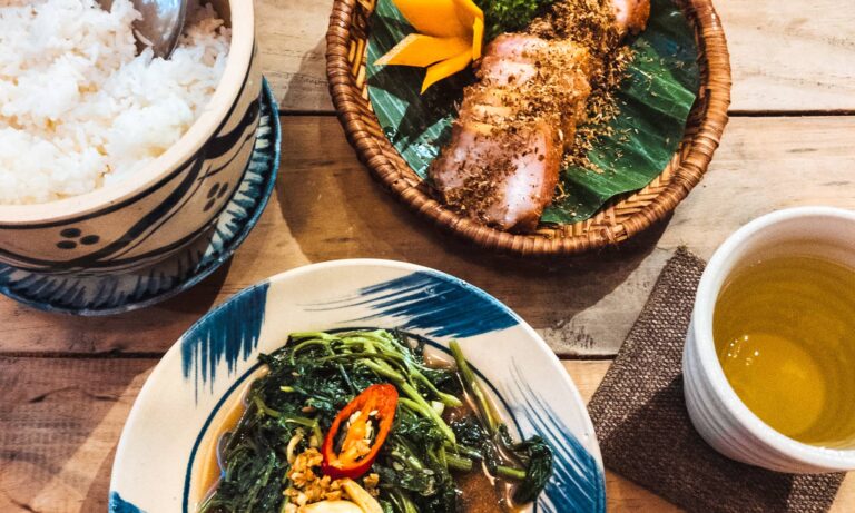 Top down view of a bowl of rice, a plate of morning glory, a plate of pork belly, and a cup of tea at Chuon Chuon Kim Restaurant in Nha Trang