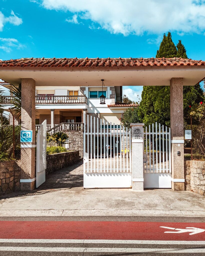 White front gate of Albergue Pallanes facing the road