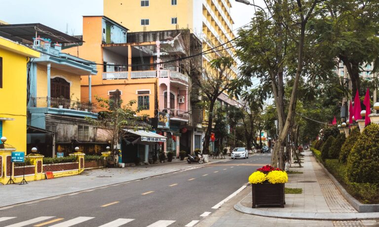 A road in Hue lined with trees and colorful, bright buildings