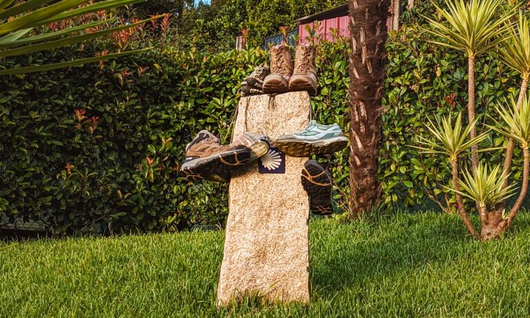 Boots and shoes on a yellow Camino de Santiago arrow marker