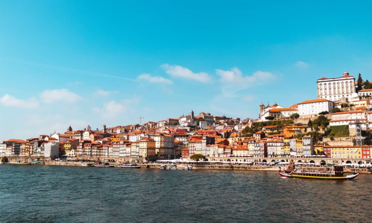 Cityscape view of Porto's white buildings with orange roofs from across the Douro River